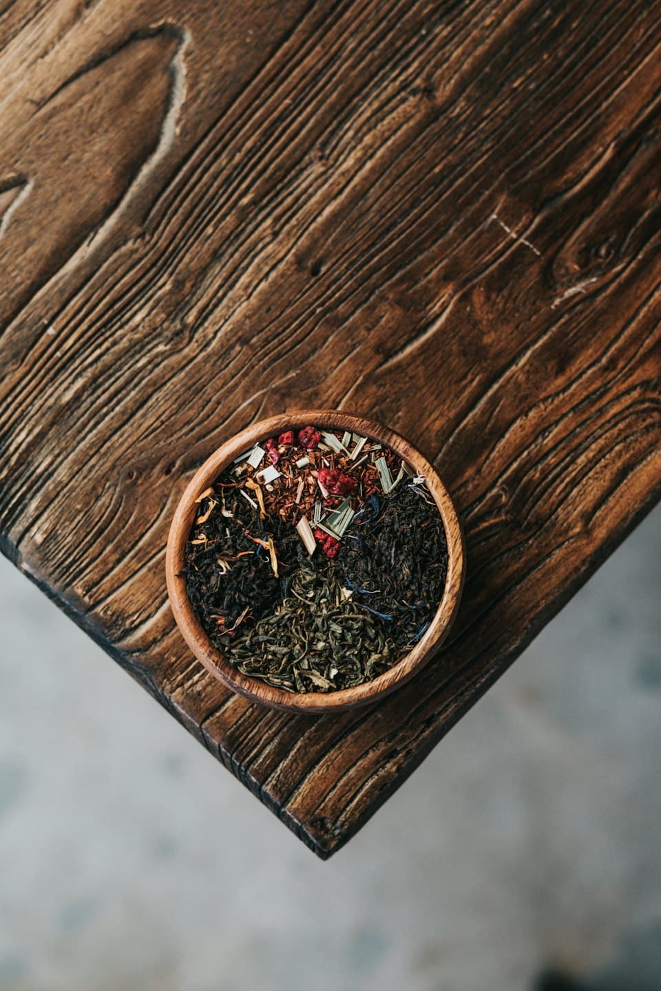 Cuenco rústico con tés de hoja suelta verdes, negros y de hierbas.