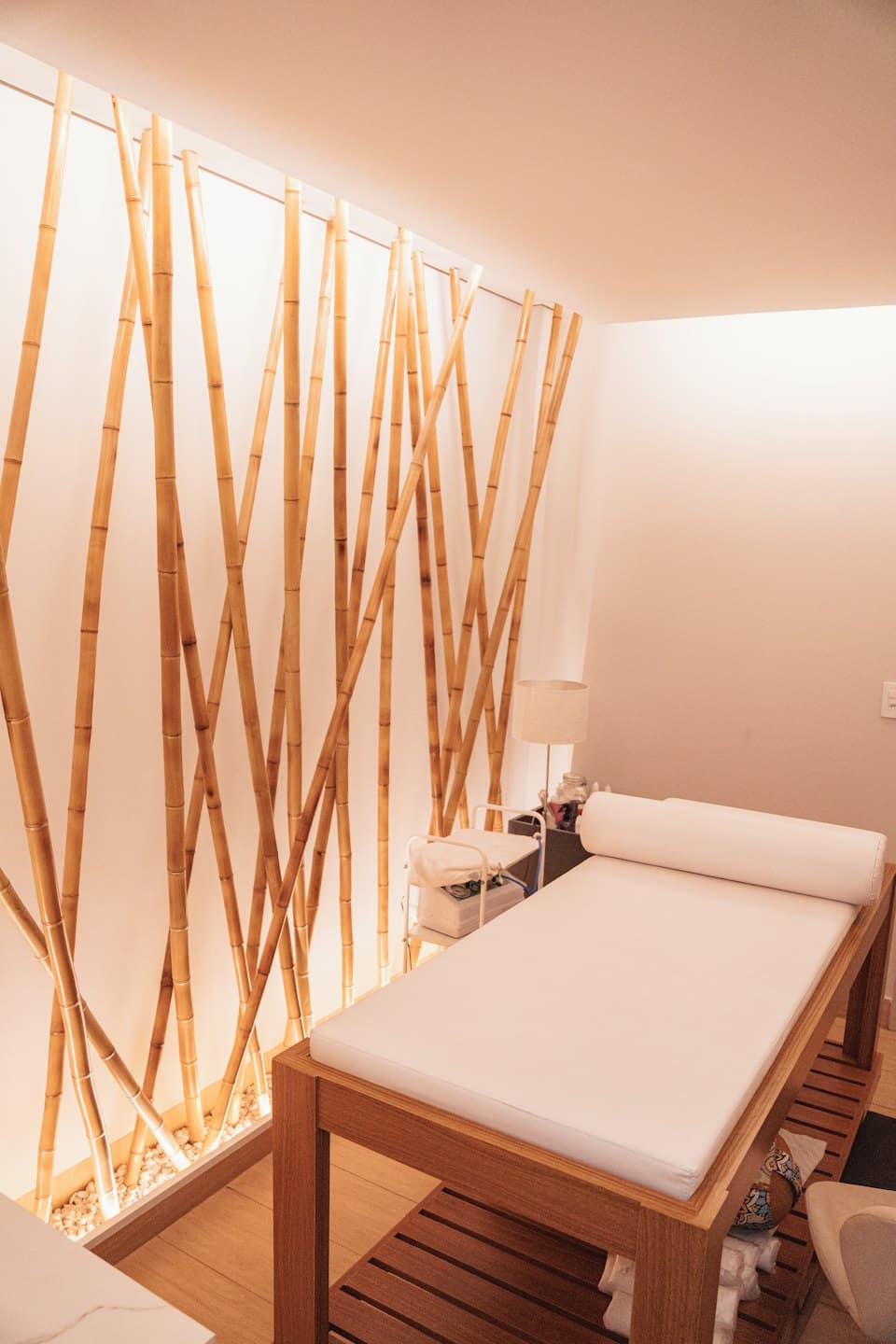 Habitación de spa vacía con pared de bambú y camilla de masaje.