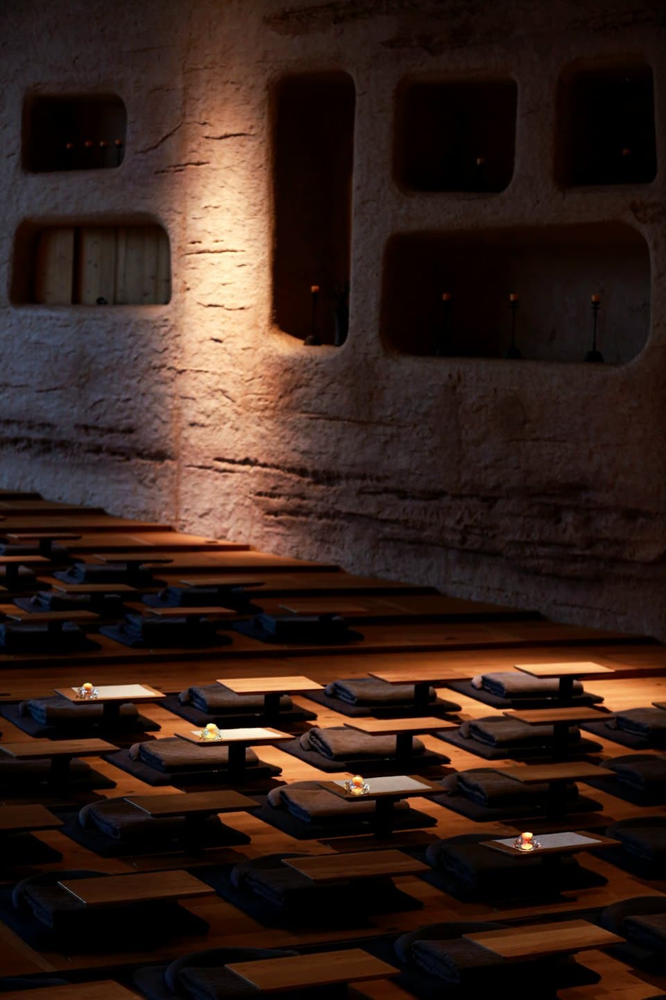 Sala de meditación vacía con cojines y velas en el suelo.