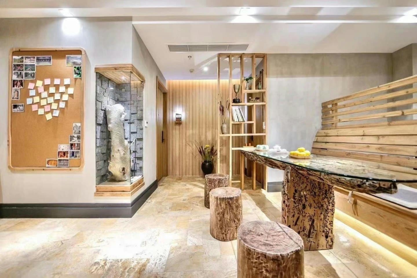 Recepción moderna con tablero de corcho, tronco de árbol esculpido y taburetes de tronco.